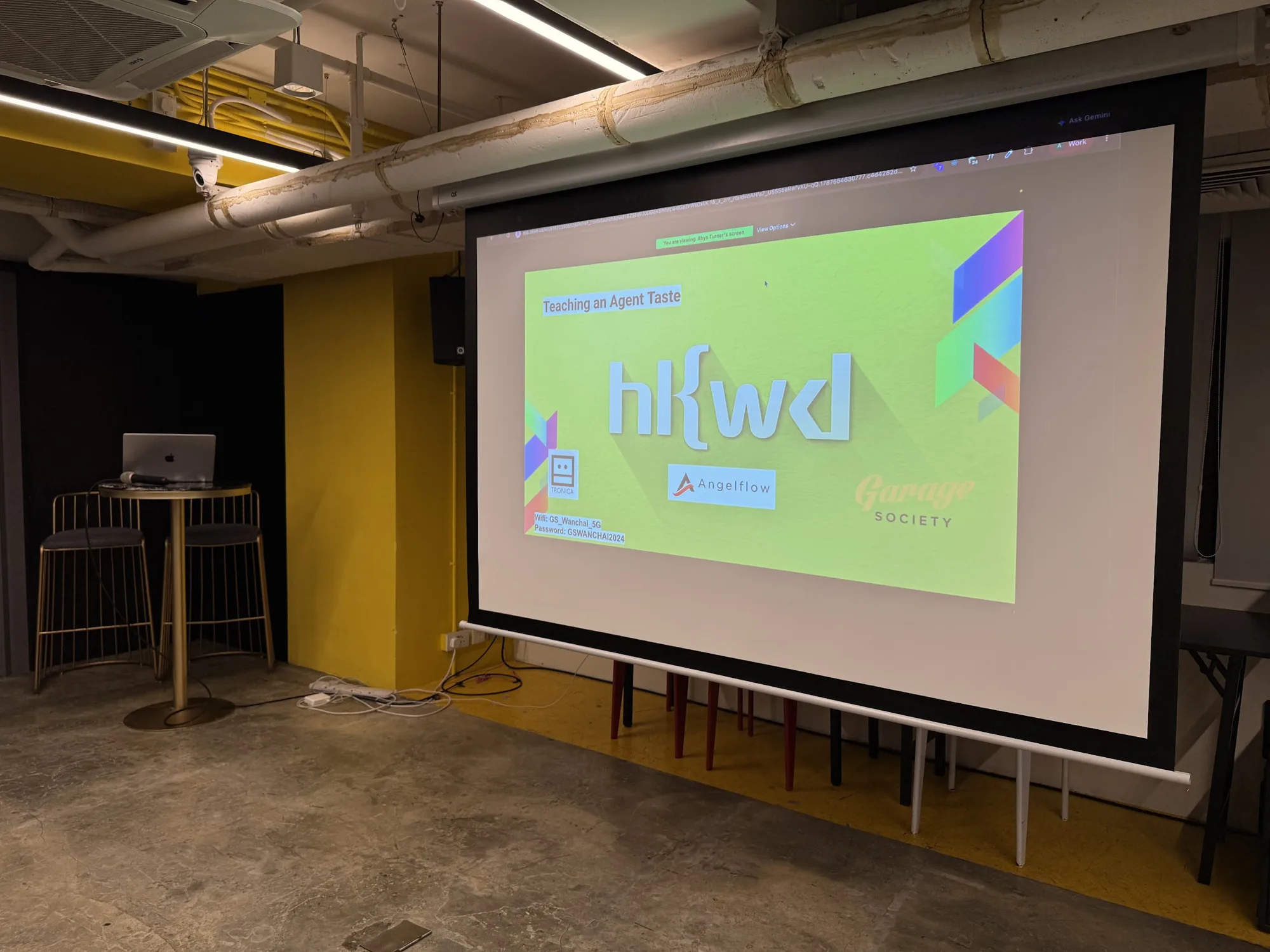 An empty meeting room at Garage Society, projector screen showing the Hong Kong Web Developers title card